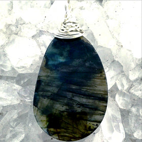 Labradorite Free Form Slice Pendant shows flashes of blue and gold. The beautiful pendant is 2 ½” x 1 ¼” with a wire wrapped bail. Mystical statement piece! New Earth Gifts