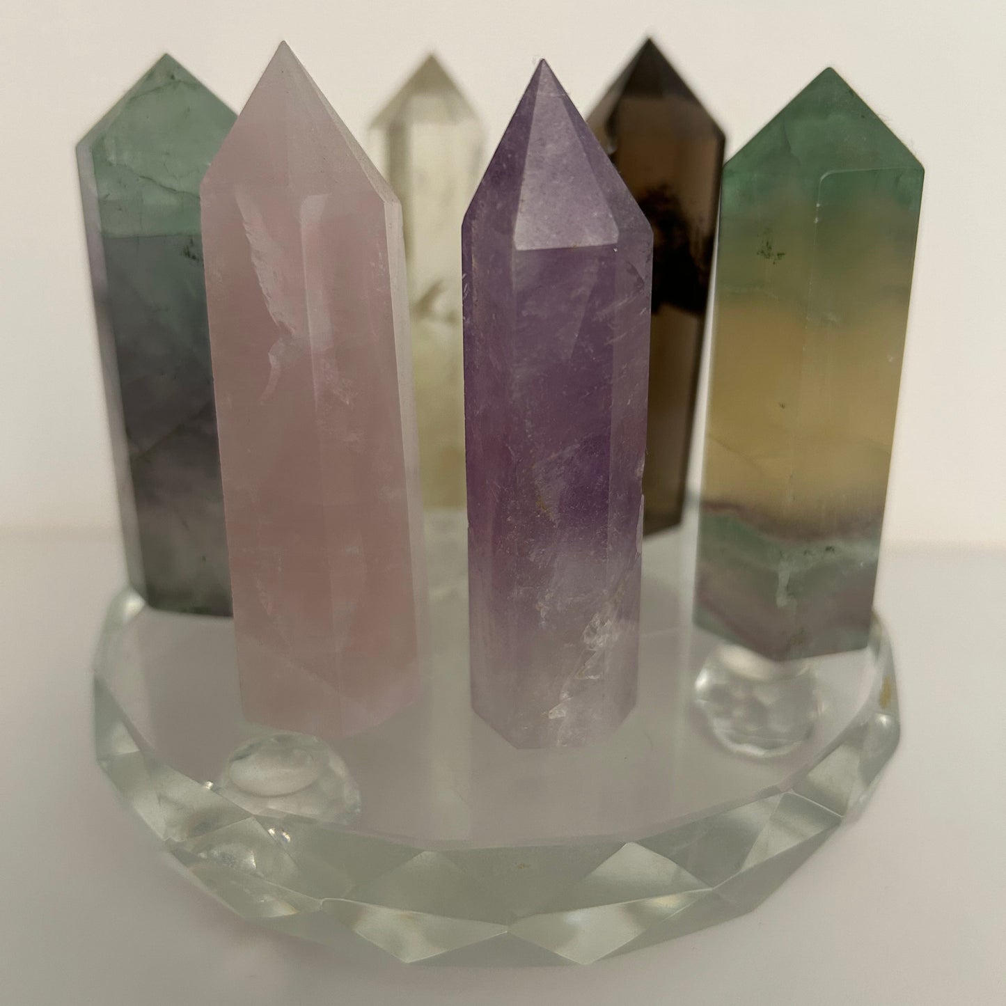 six polished crystal points displayed on a faceted glass base