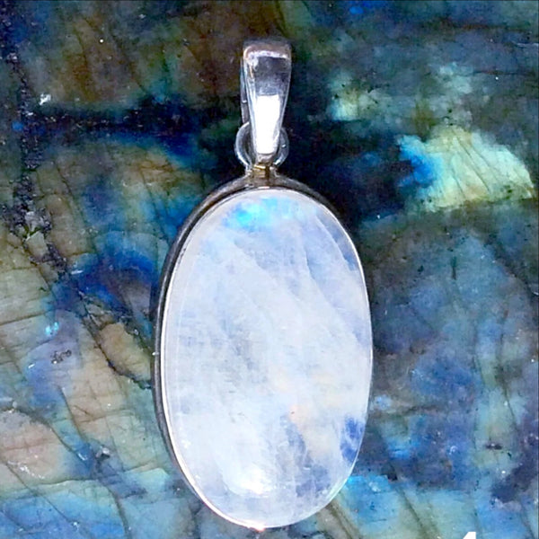 The Rainbow Moonstone Pendant Oval Sterling Pendant shows stunning rainbows in this sterling silver setting. Traditional oval cut, the pendant is 1.5" x .5". - New Earth Gifts